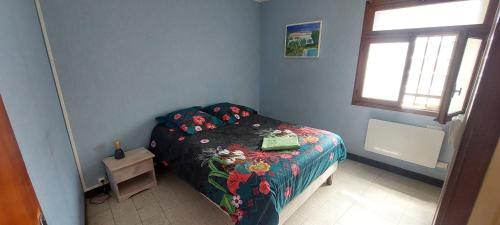 a bedroom with a bed with a floral bedspread at Maison Cosy à Rieux-Minervois in Rieux-Minervois