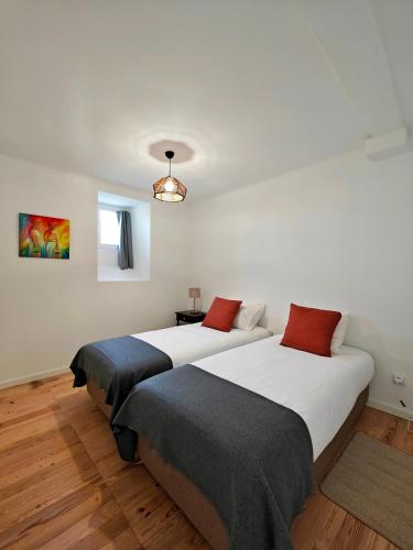 two beds in a room with white walls and wood floors at Carnide 1913 D - 1BR apt in Lisbon