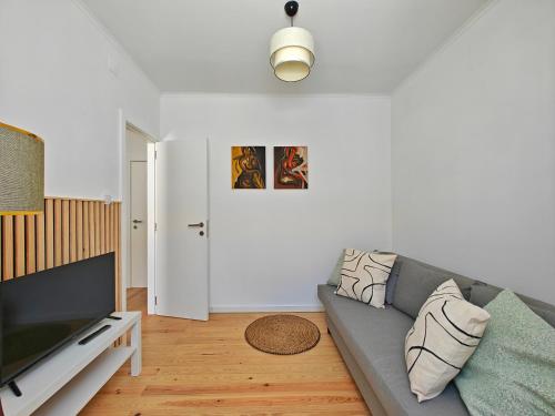 a living room with a gray couch and a flat screen tv at Carnide 1913 D - 1BR apt in Lisbon