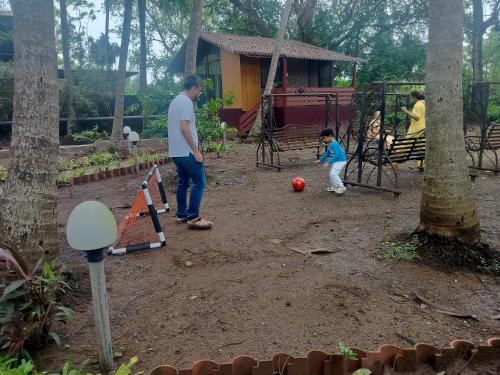 a man and a child playing with a ball in a park at Seaswan resort in Alibaug