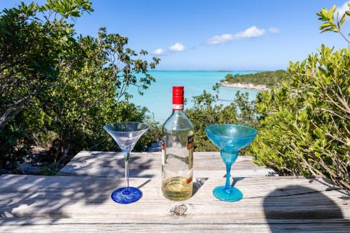 a bottle of wine and two martini glasses on a table at Waterside Home, Shaded Whirlpool Spa, Outdoor Dining, Smart TV, Amazon Prime in Providenciales