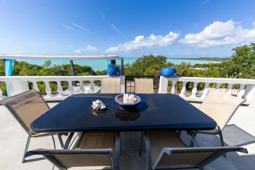 a table and chairs on a balcony with the ocean at Waterside Home, Shaded Whirlpool Spa, Outdoor Dining, Smart TV, Amazon Prime in Providenciales