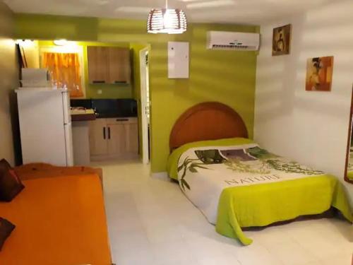a small bedroom with a bed and a refrigerator at Studio 4 personnes piscine in Sainte-Anne