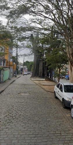 a cobblestone street with a tree and a white car at Hostel Thiago in Santa Cruz