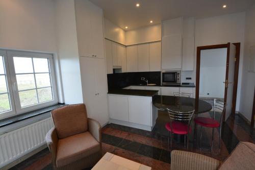 a kitchen with a glass table and a chair at PS Orion in Wenduine