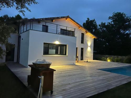 une maison blanche avec une terrasse à côté d'une piscine dans l'établissement Villa Emma, à Lit-et-Mixe