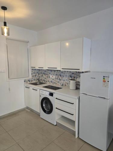 a white kitchen with a stove and a refrigerator at Margarita gardens block 6 apartment 623 in Paphos City