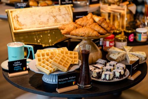 a tray of food with waffles and pastries on a table at Motel One Antwerp in Antwerp