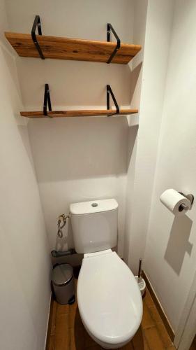 - des toilettes blanches dans une petite salle de bains pourvue d'étagères en bois dans l'établissement La Parenthèse Piscénoise, à Pézenas