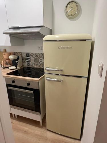 un réfrigérateur dans une cuisine avec une horloge murale dans l'établissement Appartement Cozy, à Avesnes-sur-Helpe