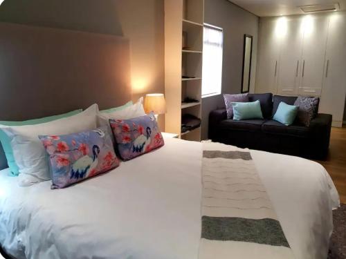 a bedroom with a bed with pillows and a couch at The Aloe House Vacation Home in Glengariff