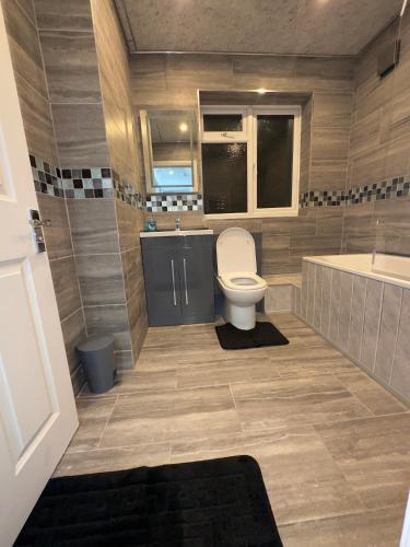 a bathroom with a toilet and a tub and a sink at Luxxe House with Hot tub and Pool table in Uxbridge
