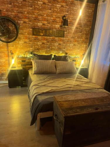 a bedroom with a bed and a brick wall at L'Atelier des Rêves in Avesnes-sur-Helpe