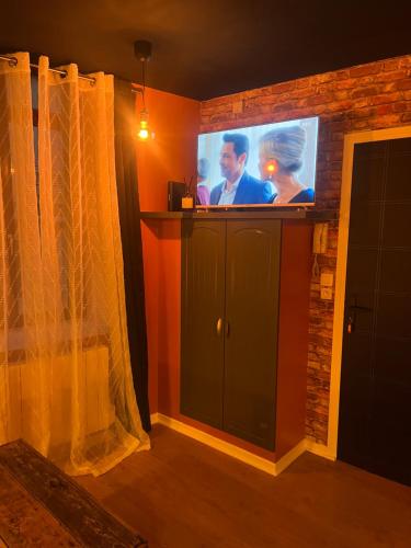 a living room with a tv on a brick wall at L'Atelier des Rêves in Avesnes-sur-Helpe