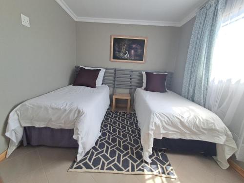 a bedroom with two beds and a window and a rug at Kaabo in Johannesburg