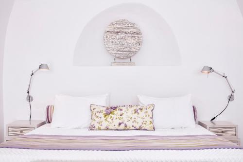 a white bedroom with a bed with two lamps at San Antonio - Small Luxury Hotels of the World in Imerovigli