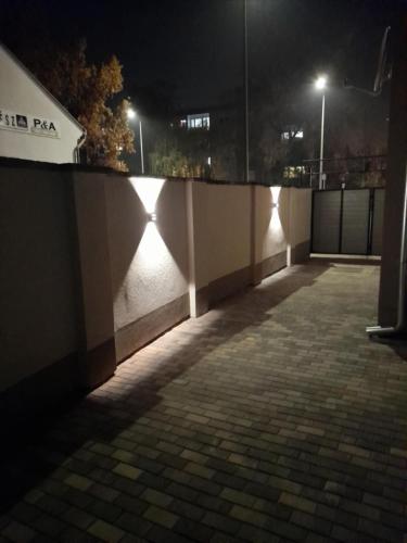 an empty street at night with lights on a wall at BB64 Apartmanház in Békéscsaba