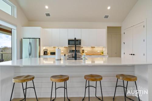 a kitchen with white cabinets and two bar stools at New Build 2BR 2BA Steiner Ranch Stay w Balcony Dining by Austin Vacay in Austin