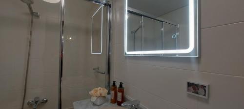 W łazience znajduje się prysznic i umywalka z lustrem. w obiekcie Apartamento Sobrevilla SDR IV Sardinero w mieście Santander