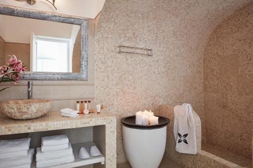 a bathroom with a tub and a sink and a mirror at San Antonio - Small Luxury Hotels of the World in Imerovigli