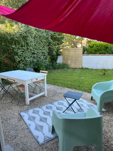 - une table de pique-nique et des chaises sous un parasol rouge dans l'établissement Maison BELMIRA, à Périgny