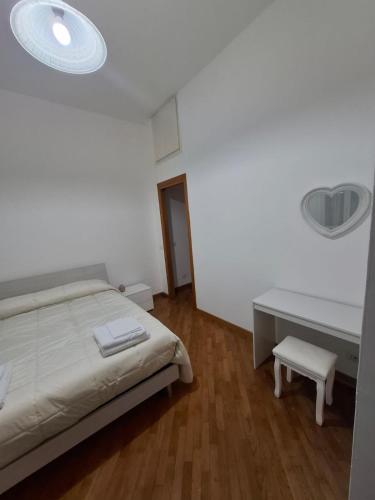 a white bedroom with a bed and a desk at Casa Mare Roma in Lido di Ostia