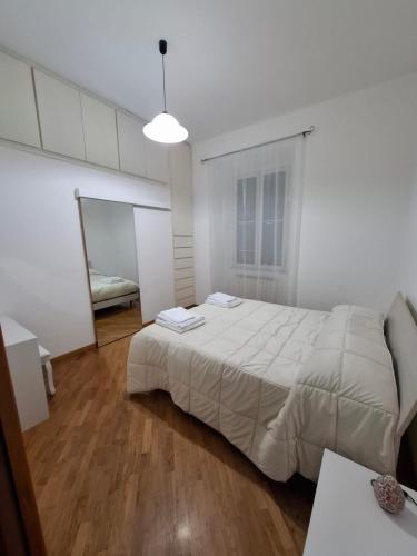 a white bedroom with a large bed and a mirror at Casa Mare Roma in Lido di Ostia