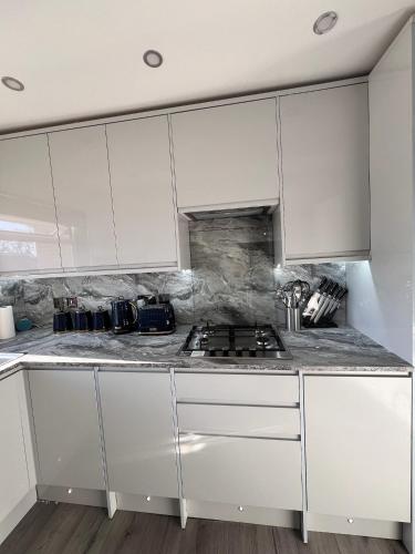 a white kitchen with a stove and white cabinets at Luxxe House with Hot tub and Pool table in Uxbridge