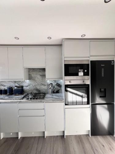 a kitchen with white cabinets and stainless steel appliances at Luxxe House with Hot tub and Pool table in Uxbridge