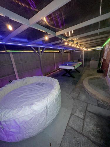 a room with a bed and a ping pong table at Luxxe House with Hot tub and Pool table in Uxbridge