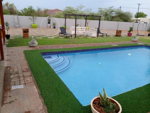 a swimming pool with green grass around it at Minnestay Guest House Palapye in Palatswe
