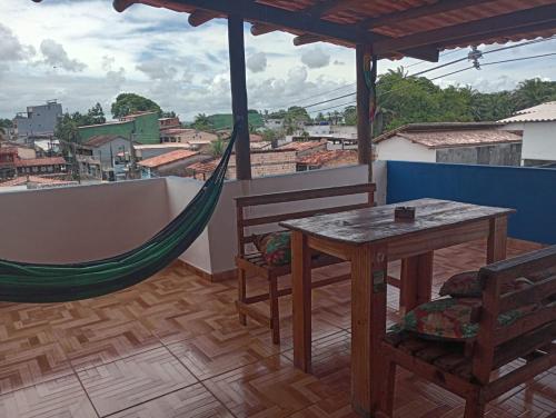a hammock and a table and chairs on a balcony at Apartamento e suítes Itacaré in Itacaré