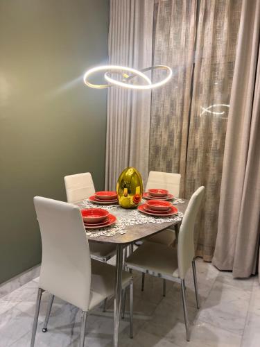 a dining room table with white chairs and red plates and a pumpkin on it at شقة أنوار مسقط in ‘Udhaybah