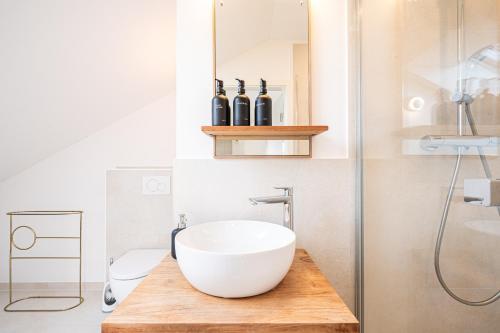 a bathroom with a white bowl sink on a wooden counter at LIBORIA: Stylisches Haus; Sauna ; 4min zum See in Seehausen am Staffelsee
