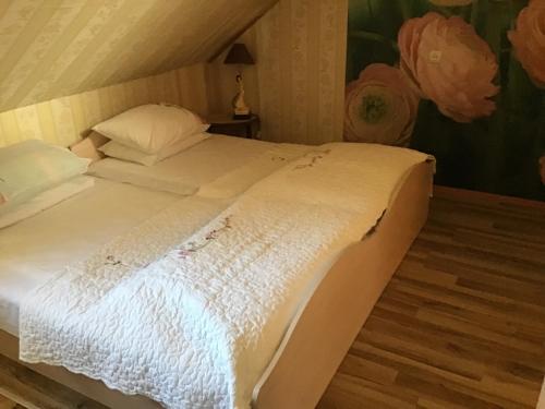 a large white bed in a room with a painting at Šturmų Sodyba in Ventė