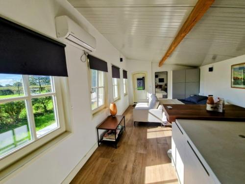 a kitchen and living room with a couch and windows at Natuurhuisje De kleine Varenhorst in Breedenbroek