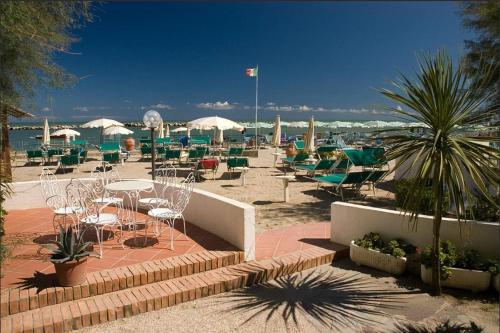 a group of chairs and tables and umbrellas on a beach at Hotel Napoleon in San Mauro a Mare