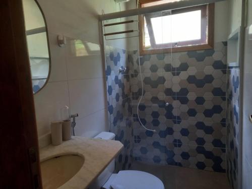 a bathroom with a toilet and a sink and a shower at Casinha mar e mato in Ubatuba