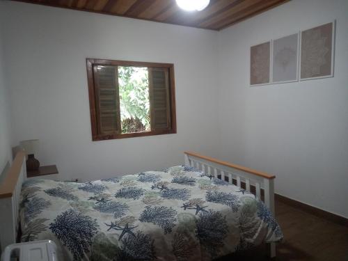 a bedroom with a bed with a comforter and a window at Casinha mar e mato in Ubatuba
