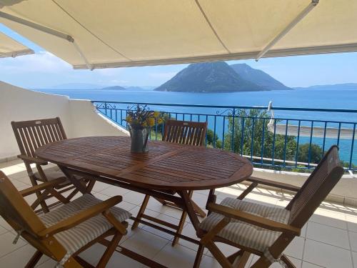 a wooden table and chairs on a balcony with a view at Kalamos Bay View in Panagoúla