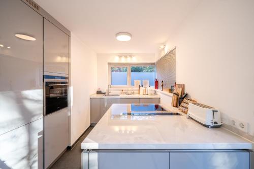 a large white kitchen with a sink and a microwave at LIBORIA I Stylisches Haus I Sauna I Wellness in Starnberg