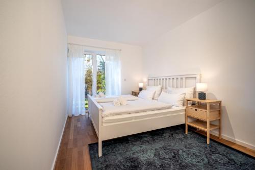 a white bedroom with a bed and a window at LIBORIA I Stylisches Haus I Sauna I Wellness in Starnberg