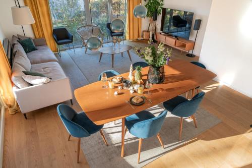 a living room with a wooden table and blue chairs at LIBORIA I Stylisches Haus I Sauna I Wellness in Starnberg