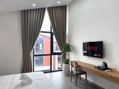 a bedroom with a television on a wall with a table at Hayden Home Ocean Park 3 in Ðình Loan