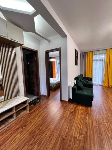 a living room with a green couch and wooden floors at Hillstory Borjomi tba in Tsemi