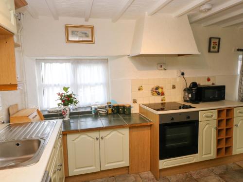 a kitchen with white cabinets and a black stove top oven at Stable Cottage in Haverfordwest