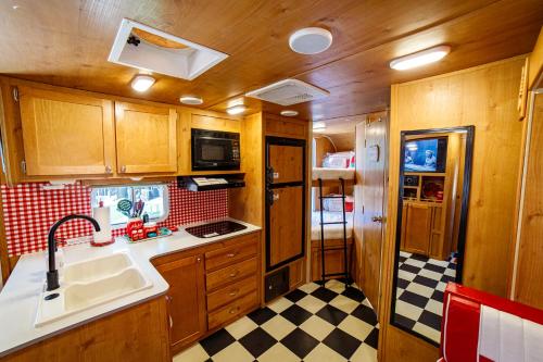 uma cozinha com armários de madeira e um piso em xadrez em Darling Daisy Retro RV Adventure em El Cajon