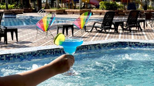 a person holding a drink in a swimming pool at Tequendama Hotel Campestre Villavicencio in Villavicencio