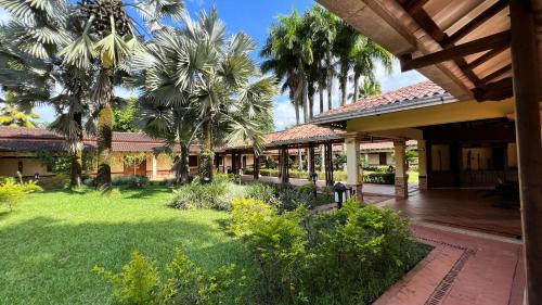 a house with a courtyard with palm trees and a yard at Tequendama Hotel Campestre Villavicencio in Villavicencio