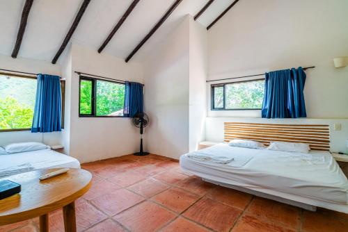 two beds in a room with blue curtains at Casa Matiz - Vistas increíbles cerca de Anapoima in Apulo